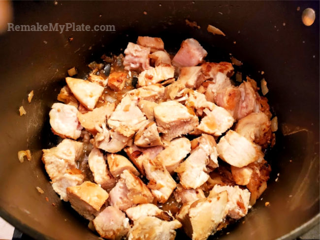 Diced chicken and onions being cooked in pot