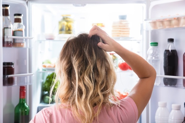 confused woman looking into the refrigerator