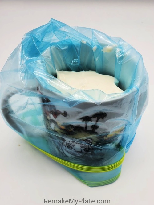 place the plastic bag being used as a piping bag into a cup and fold down the edges around the cup