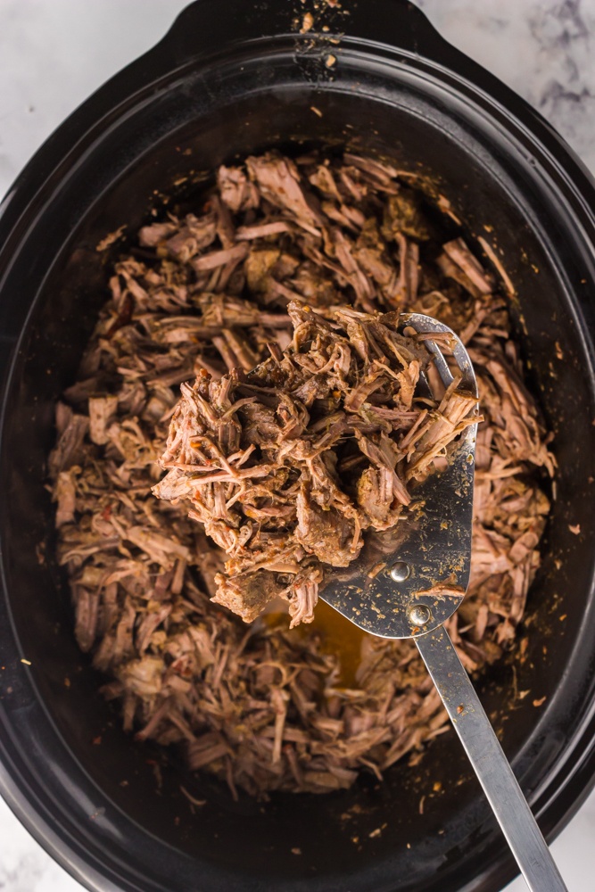 shredded slow cooker barbacoa beef on a serving spoon