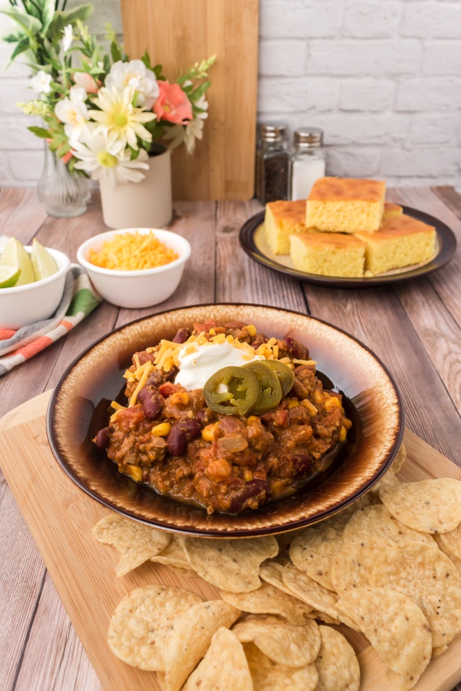 Easy pumpkin chili in a bowl with cornbread and shredded cheese