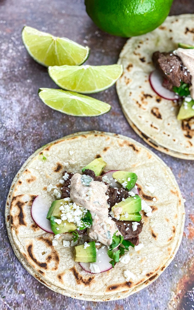 carne asada tacos topped with avocado and cotija cheese