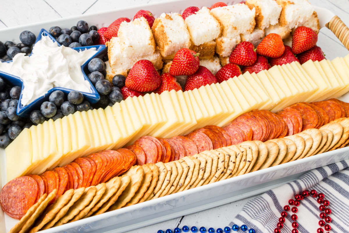 patriotic charcuterie board displayed on a table with red, white and blue beads