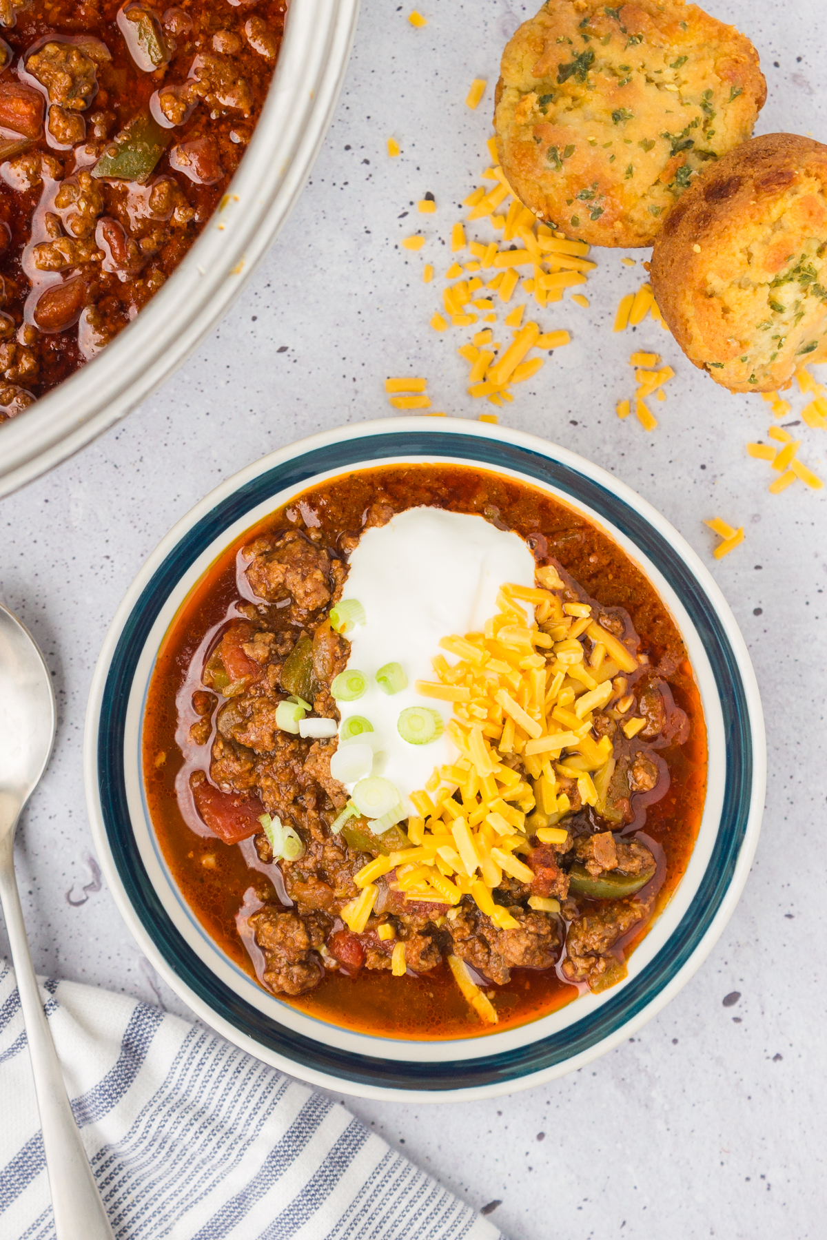 beef and chorizo chili in a bowl topped with shredded cheese, sour cream and green onions
