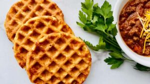 Keto Cornbread Chaffles featured 3 fanned chaffles on the left and right is a partial bowl of chili w parsley e1623872803574.jpgfit12002c676ssl1