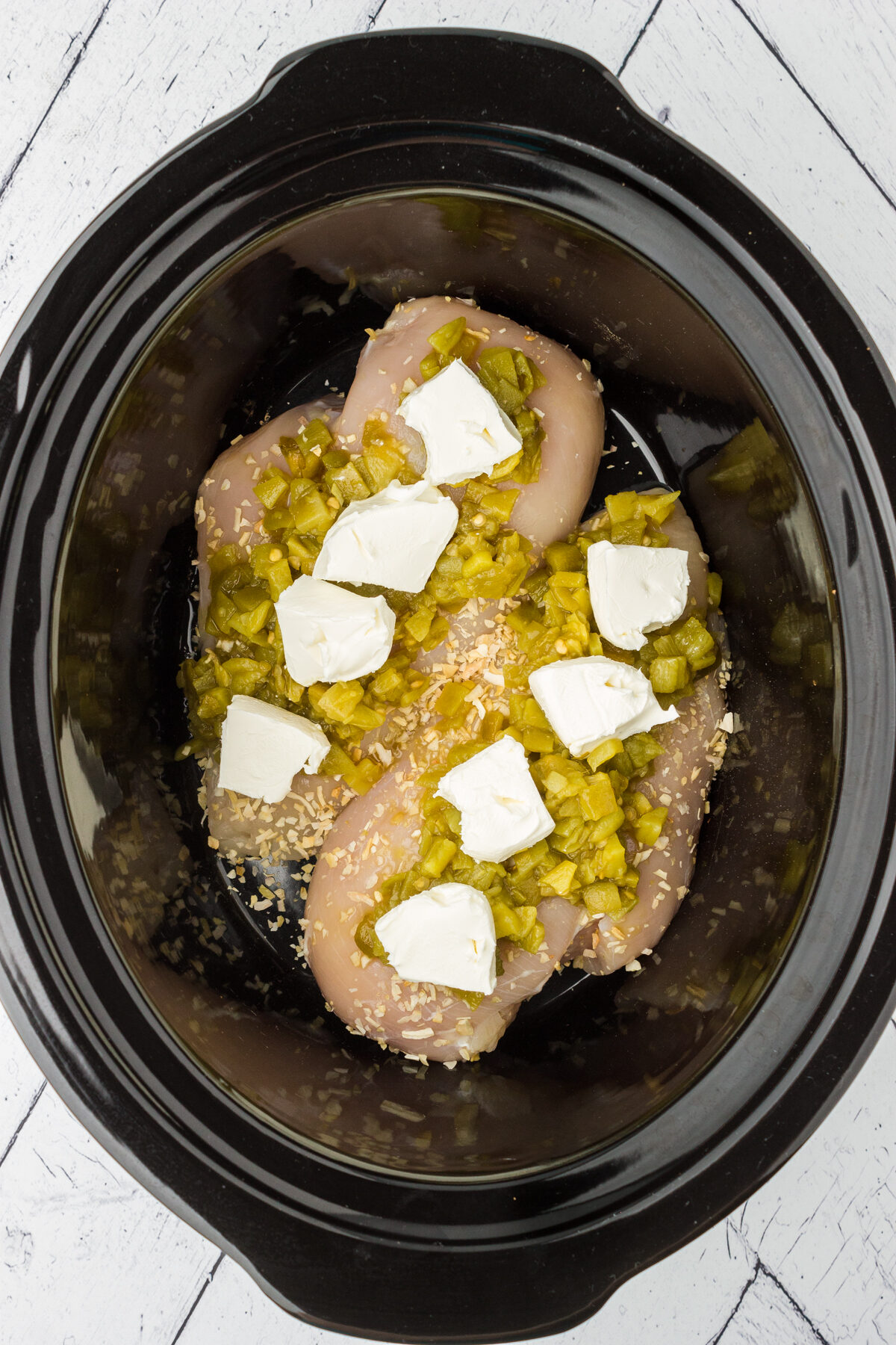 layering the simple ingredients for this shredded chicken recipe into the slow cooker