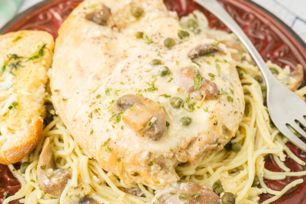 copycat cheesecake factory’s chicken piccata recipe on a plate with a slice of garlic bread