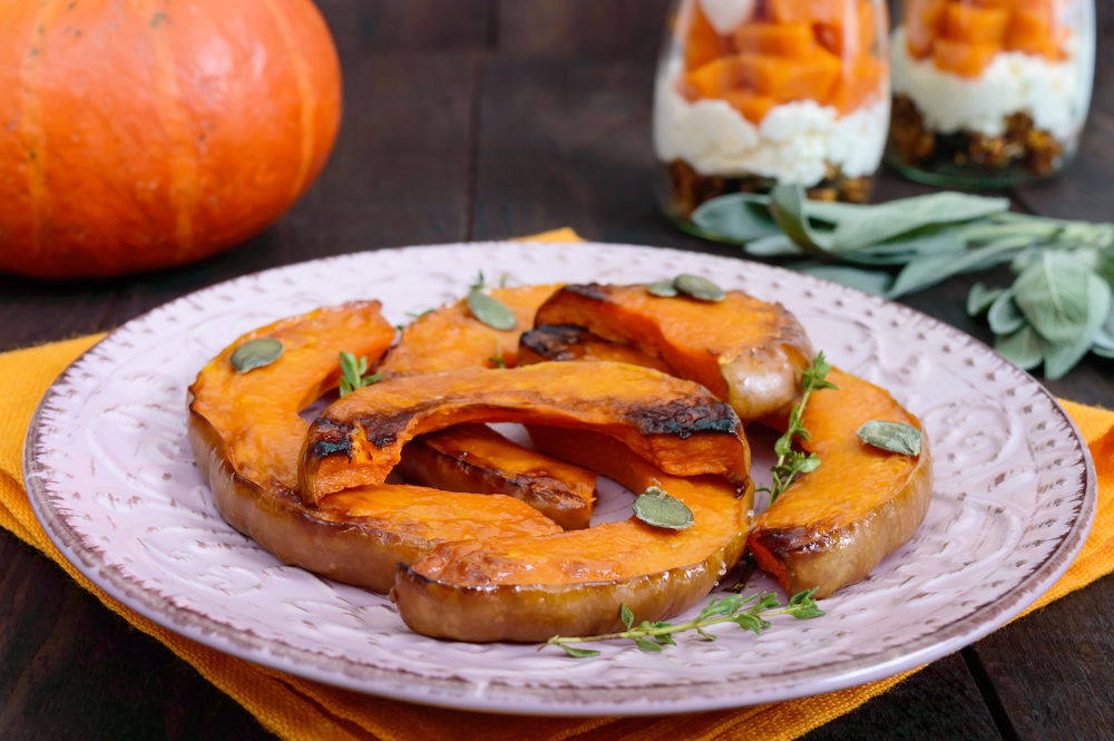 slices of baked pumpkin on a plate topped with pumpkin seeds