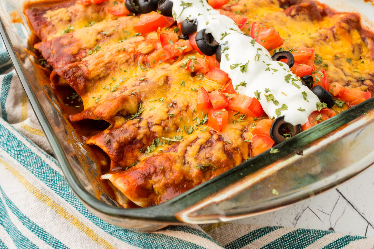 Healthy chicken enchiladas topped with a red sauce in a baking dish