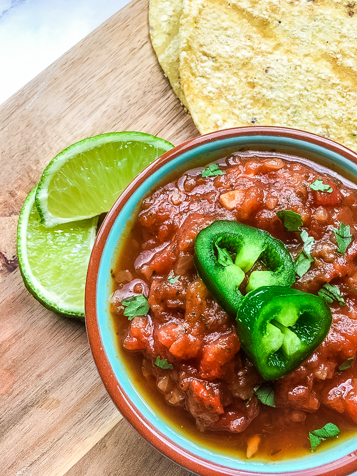 spicy salsa in a bowl with tortilla chips and limes on the table