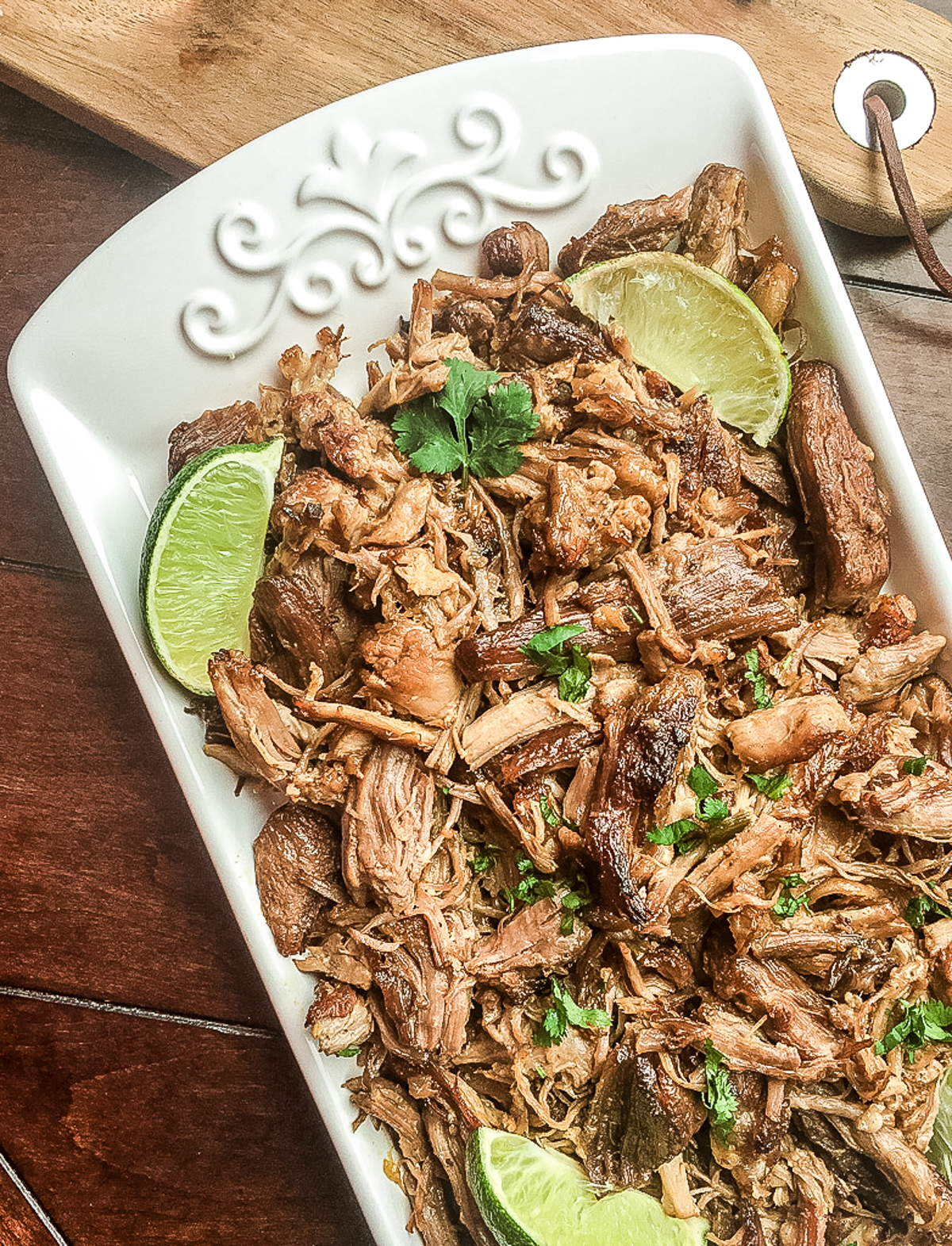 finished shredded pork carnitas in a dish with lime wedges