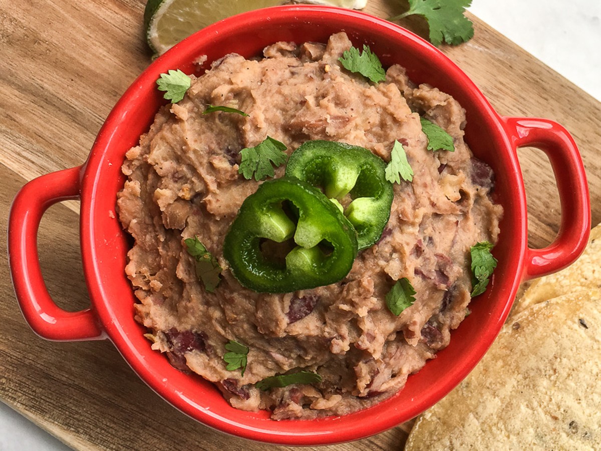 Restaurant Style Homemade Refried Beans in a bowl topped with jalapeno slices