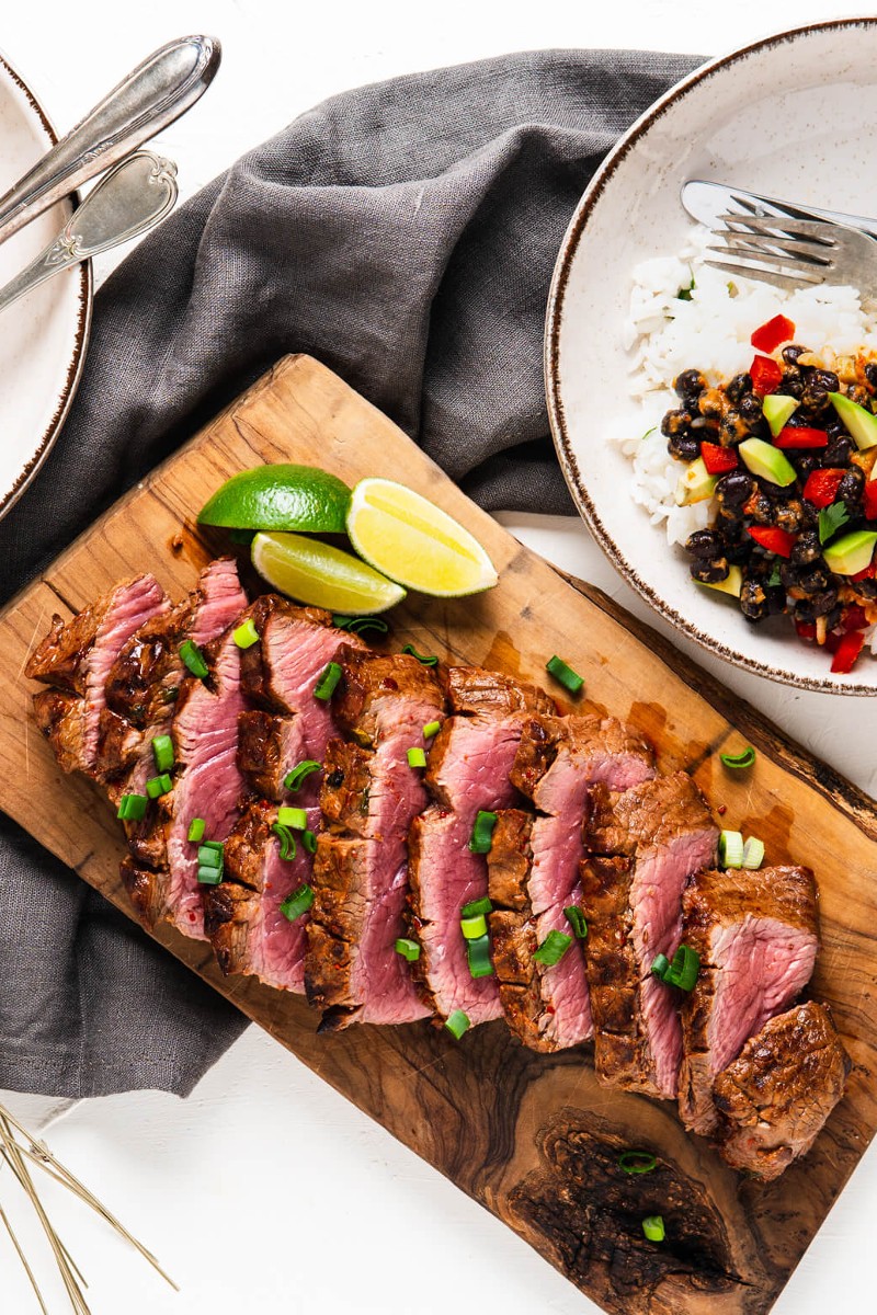 sliced marinated flat iron steak on a cutting board