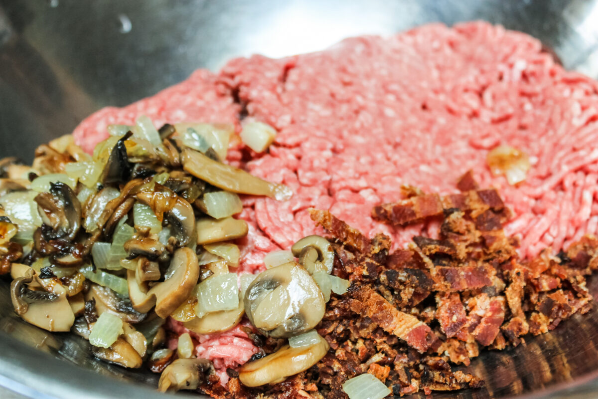 adding the cooked mushroom, onions and bacon to the ground beef