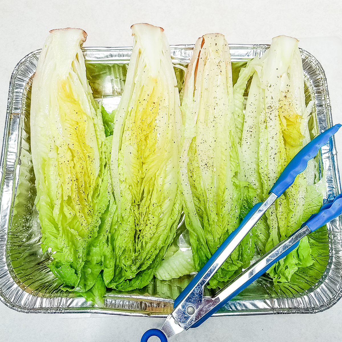 romaine heart split in half, coated with olive oil and sprinkled with salt and black pepper
