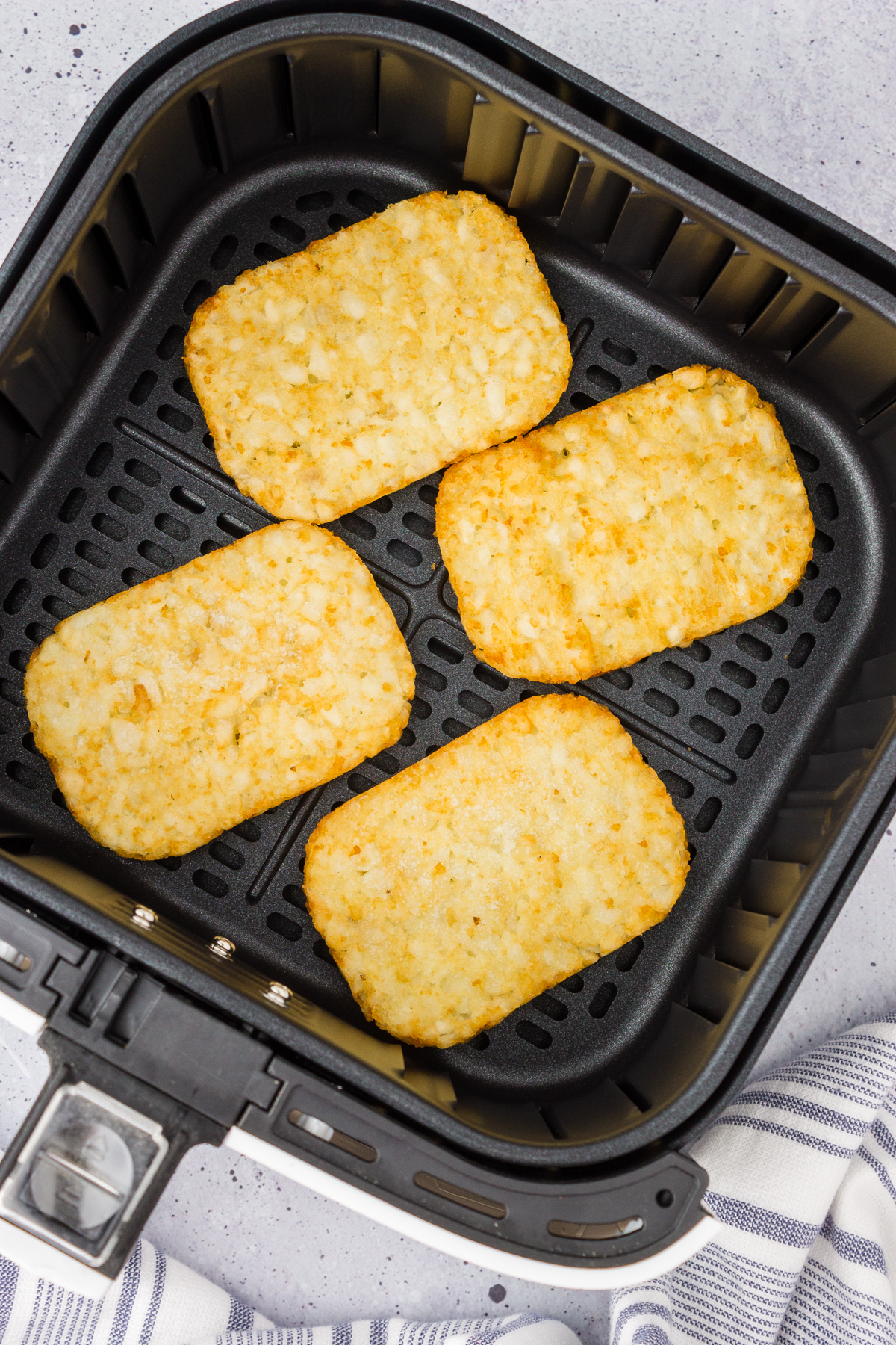 hash brown patties placed in an air fryer evenly spaced