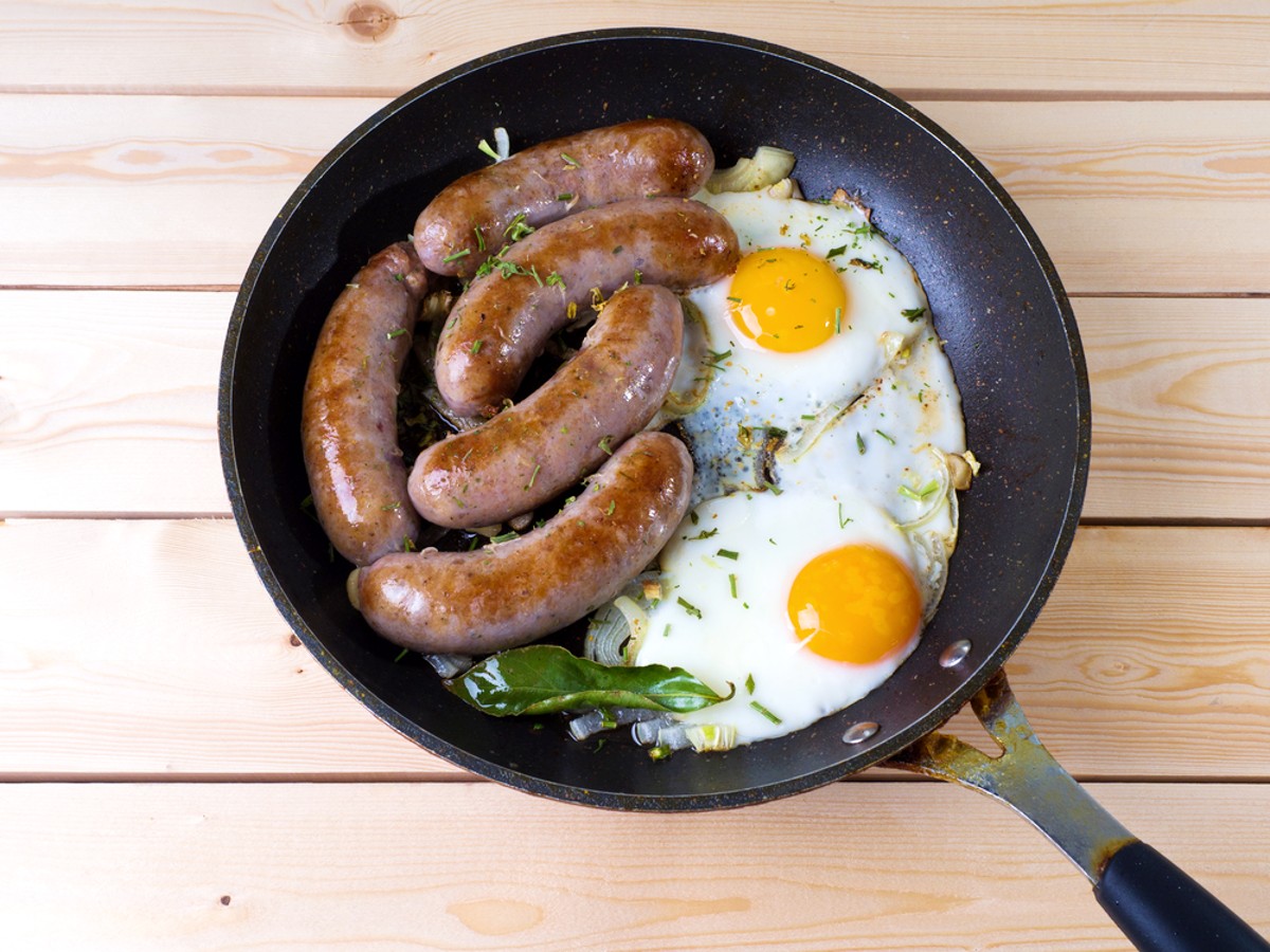 country sausage with fried eggs cooking in a pan