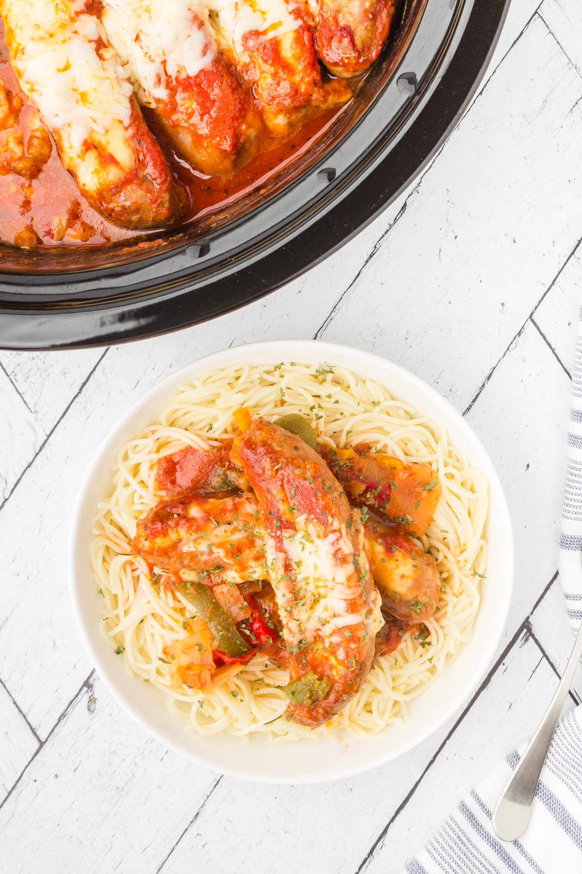 Stuffed Italian sausage and peppers in a crockpot and served on a plate with shirataki noodles.