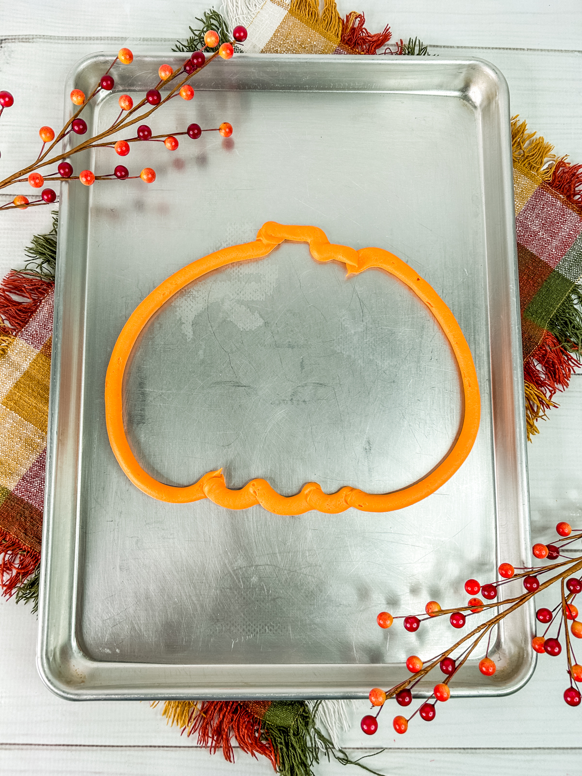 Piping frosting to create a pumpkin outline on the charcuterie board.