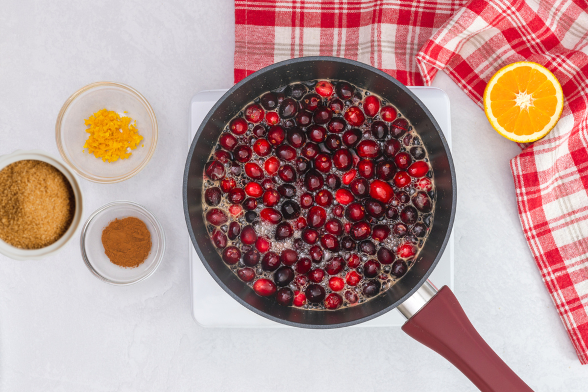 medium sauce pan filled with cranberries simmering in a half cup of water