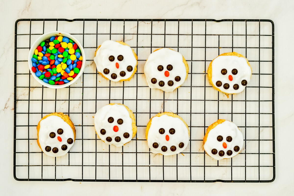 adding candies to make eyes, nose and mouth of the cookie snowman