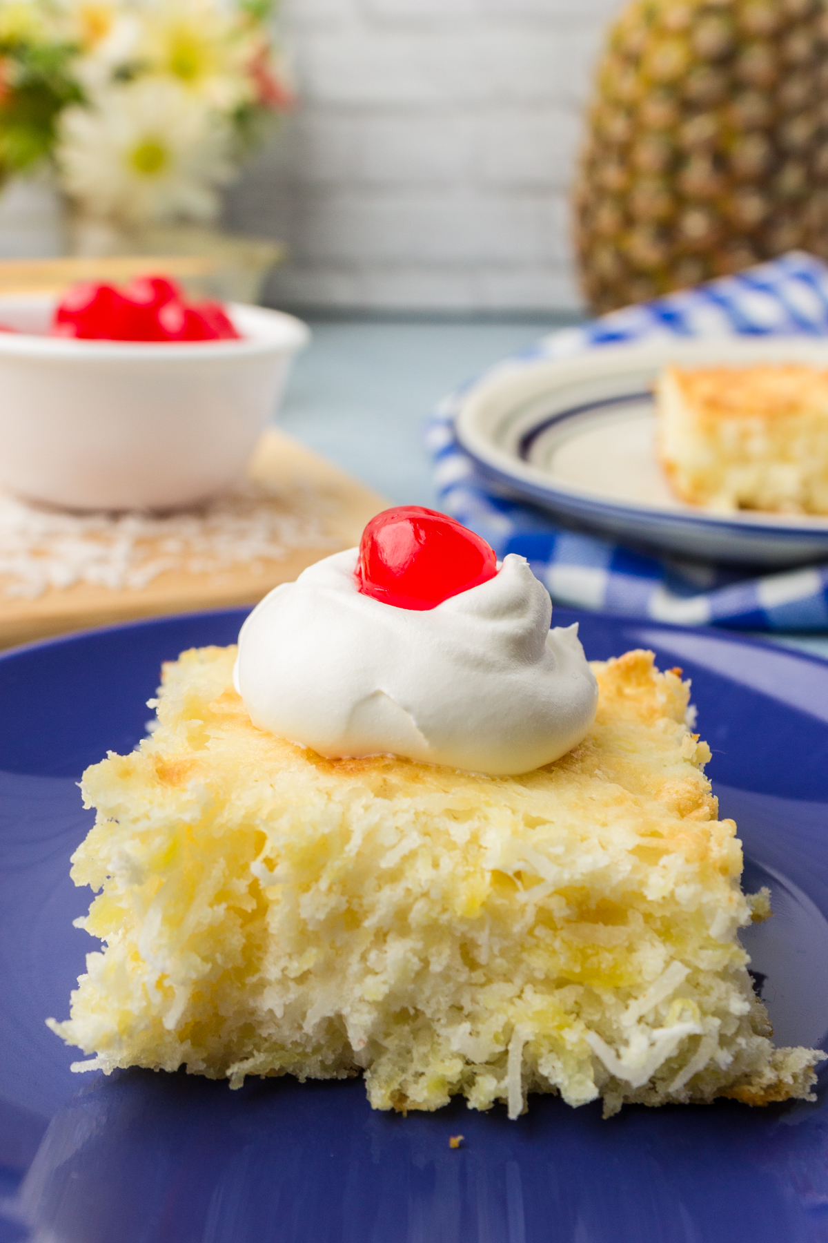 slice of pineapple coconut dump cake topped with a cherry on a plate