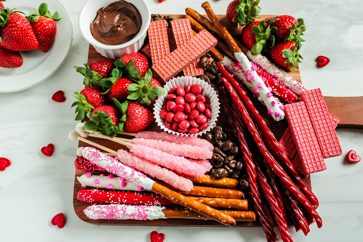 valentine’s charcuterie board filled with chocolate dipped pretzels, strawberries and candy