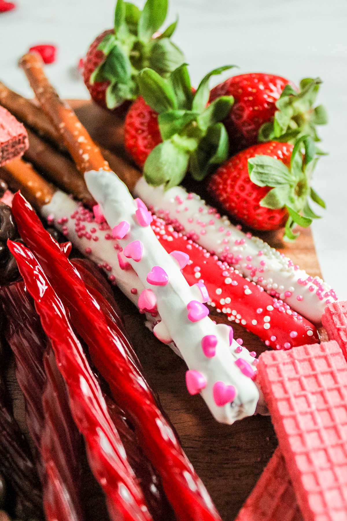 valentines day dessert snack board filled with fresh fruit and chocolate dipped pretzels