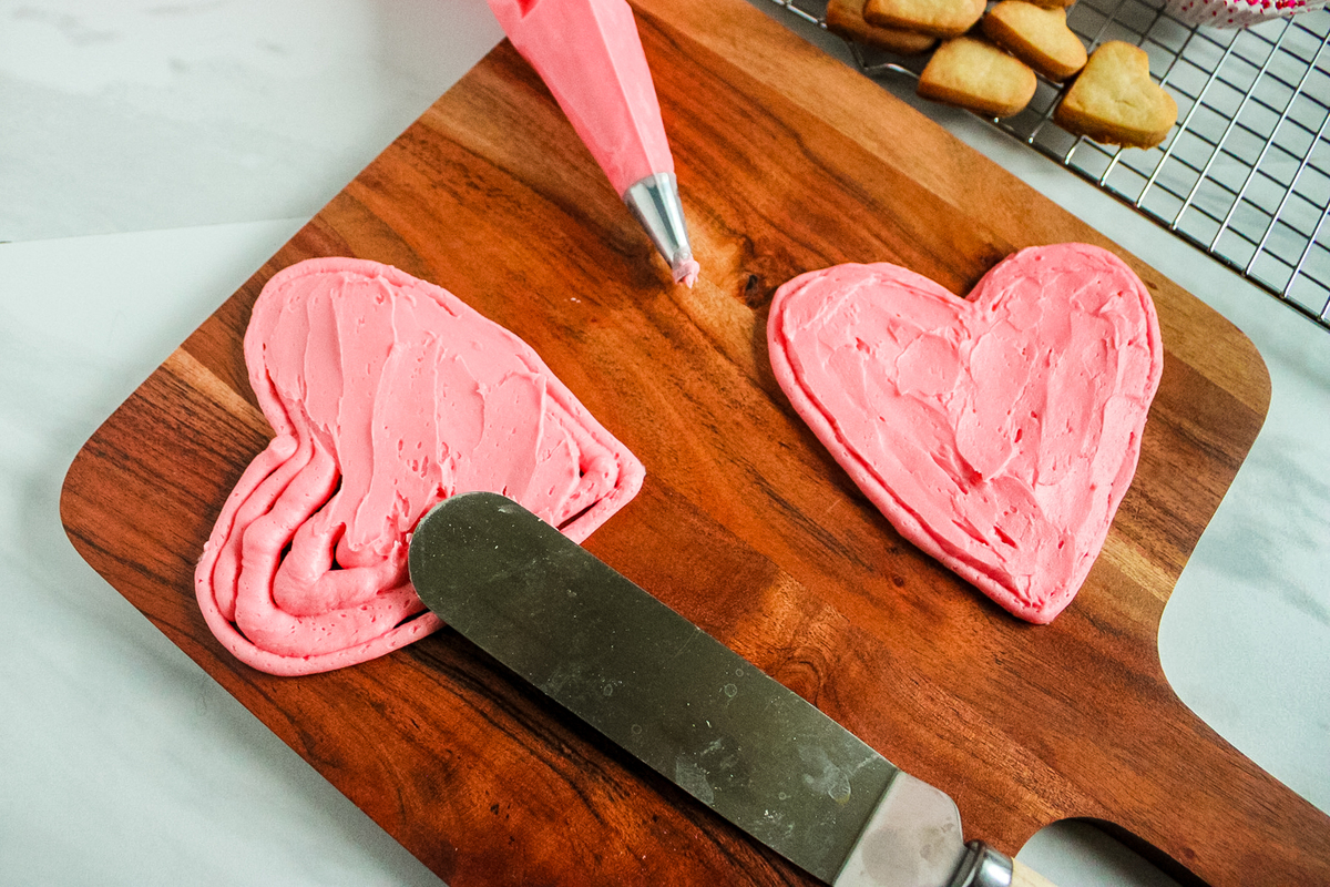 piping the frosting into heart shapes on the charcuterie board