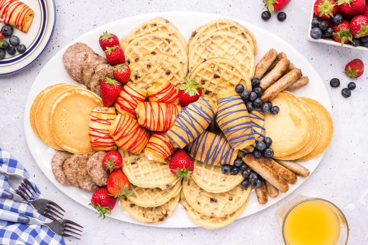 Easter breakfast charcuterie board filled with waffles, pancakes, sausage, cream cheese filled crescent rolls and fresh fruit