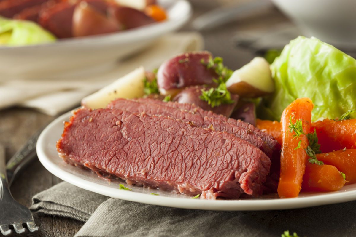 plate filled with corned beef slices, cabbage wedges, carrots and boiled red potatoes