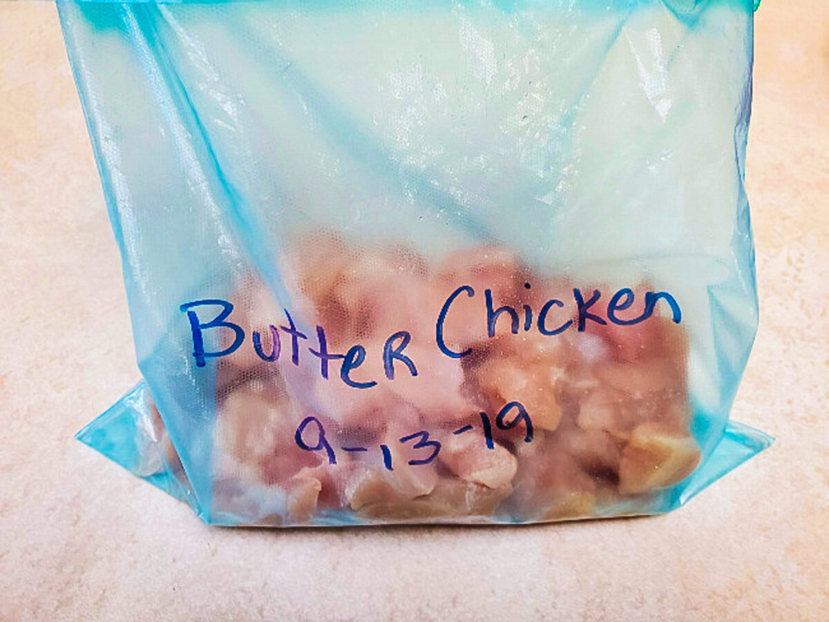 freezer bag filled with diced chicken, onion and garlic.