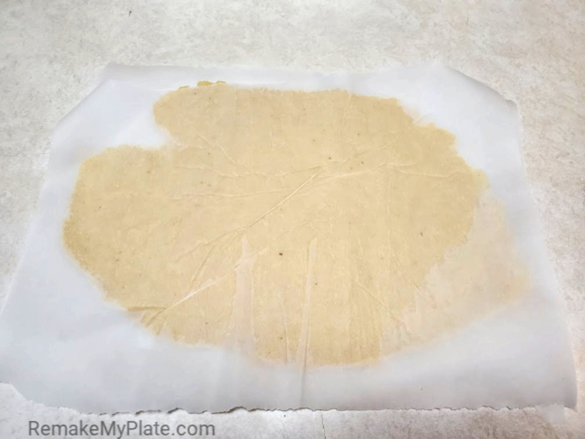 rolling out the fathead dough between pieces of parchment paper