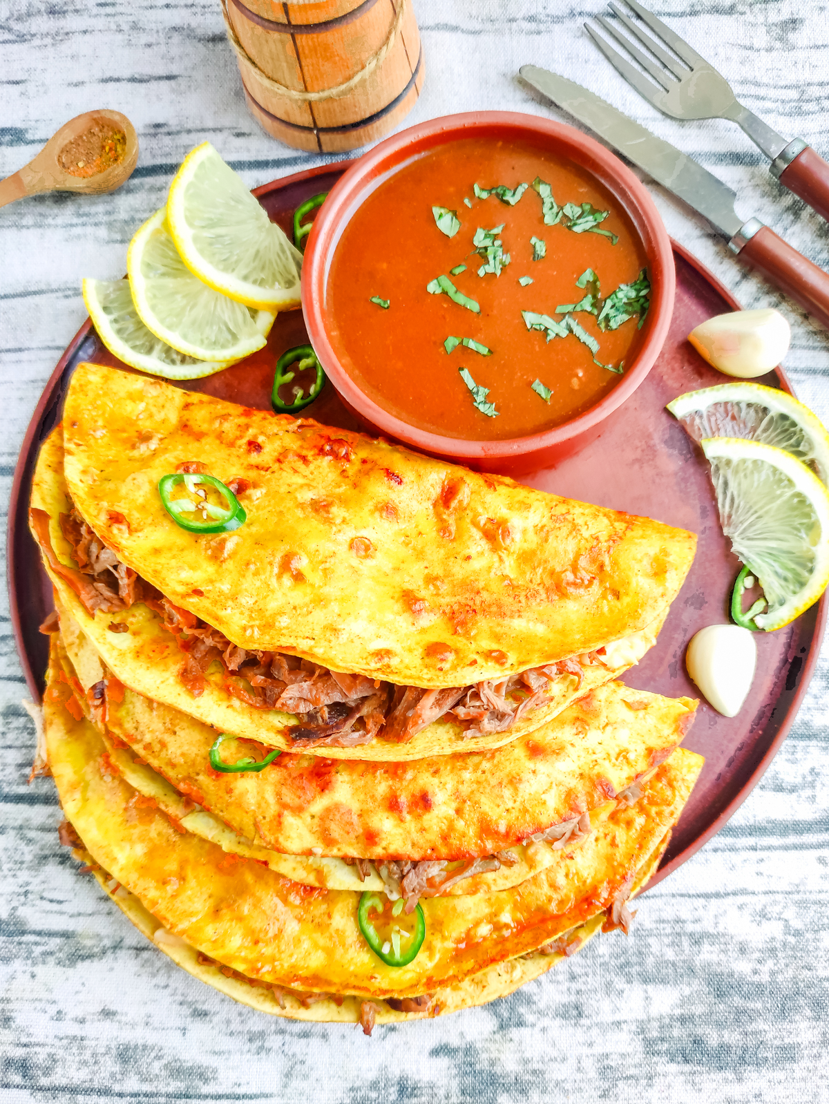 Quesabirria Tacos on a plate with dipping sauce on the side