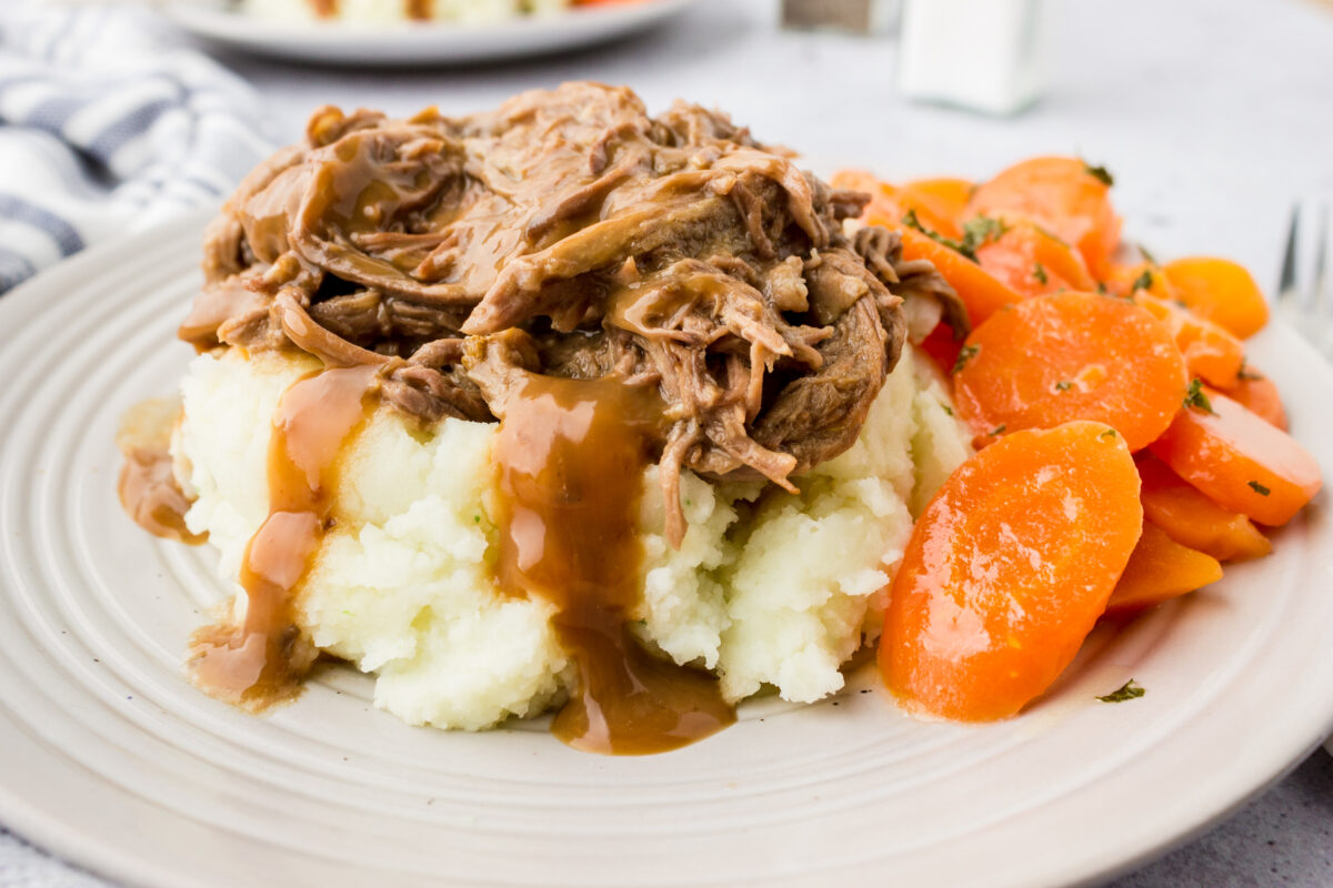 Easy slow cooker pot roast on a plate with a side of sweet carrots 