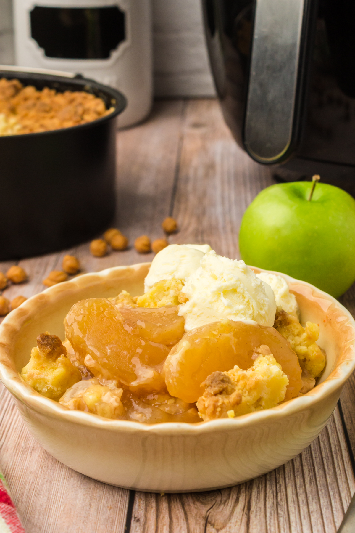 caramel apple pie filling dump cake in a bowl with scoops of vanilla ice cream