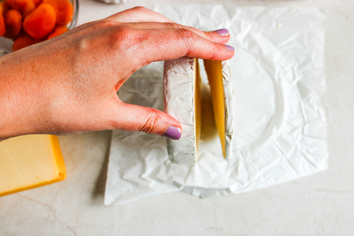 slicing the top off the round of brie cheese