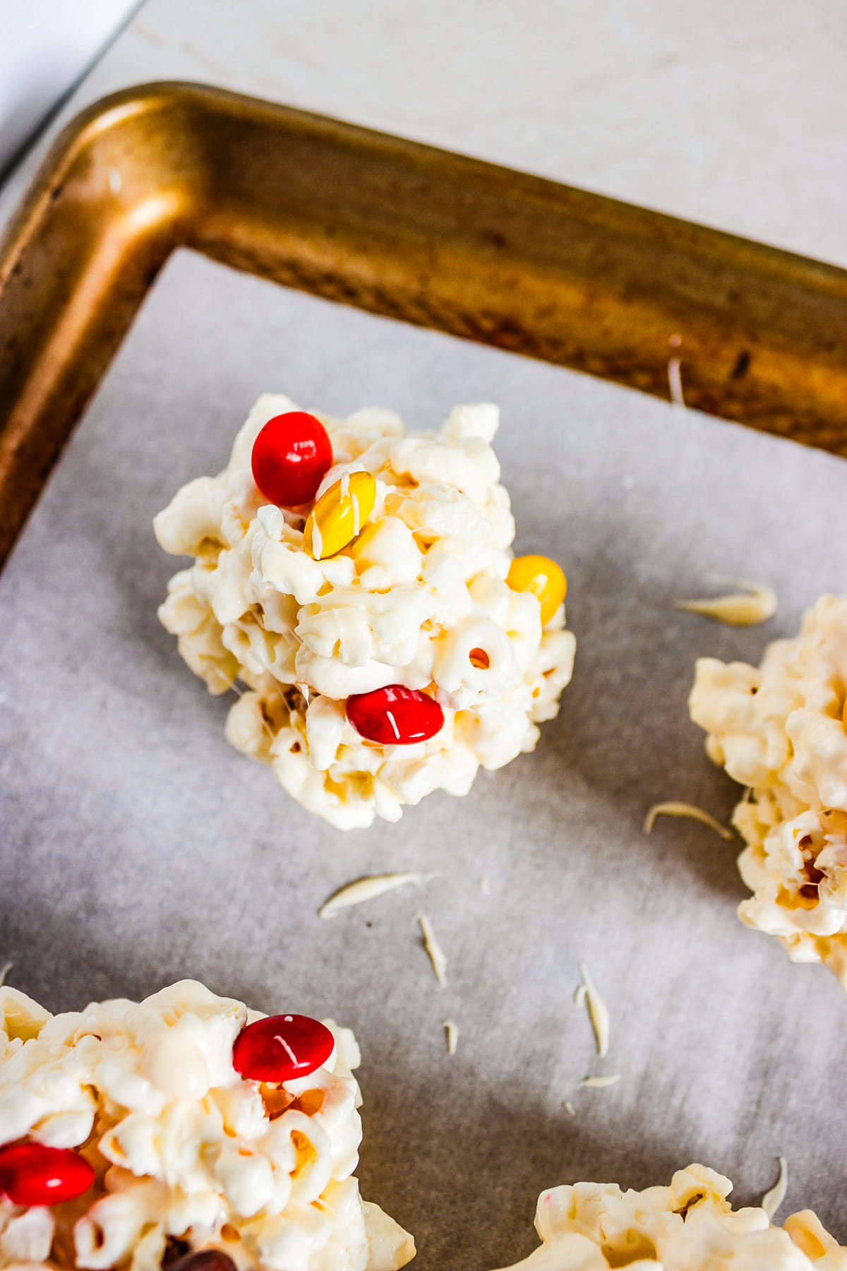 scoops of popcorn mixture cooling on a baking sheet