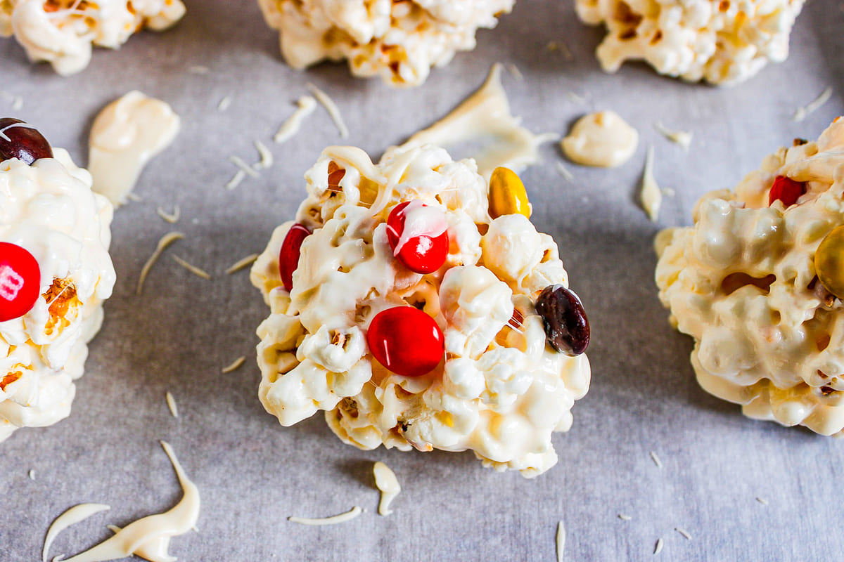 halloween popcorn balls drizzled with white chocolate on a baking sheet