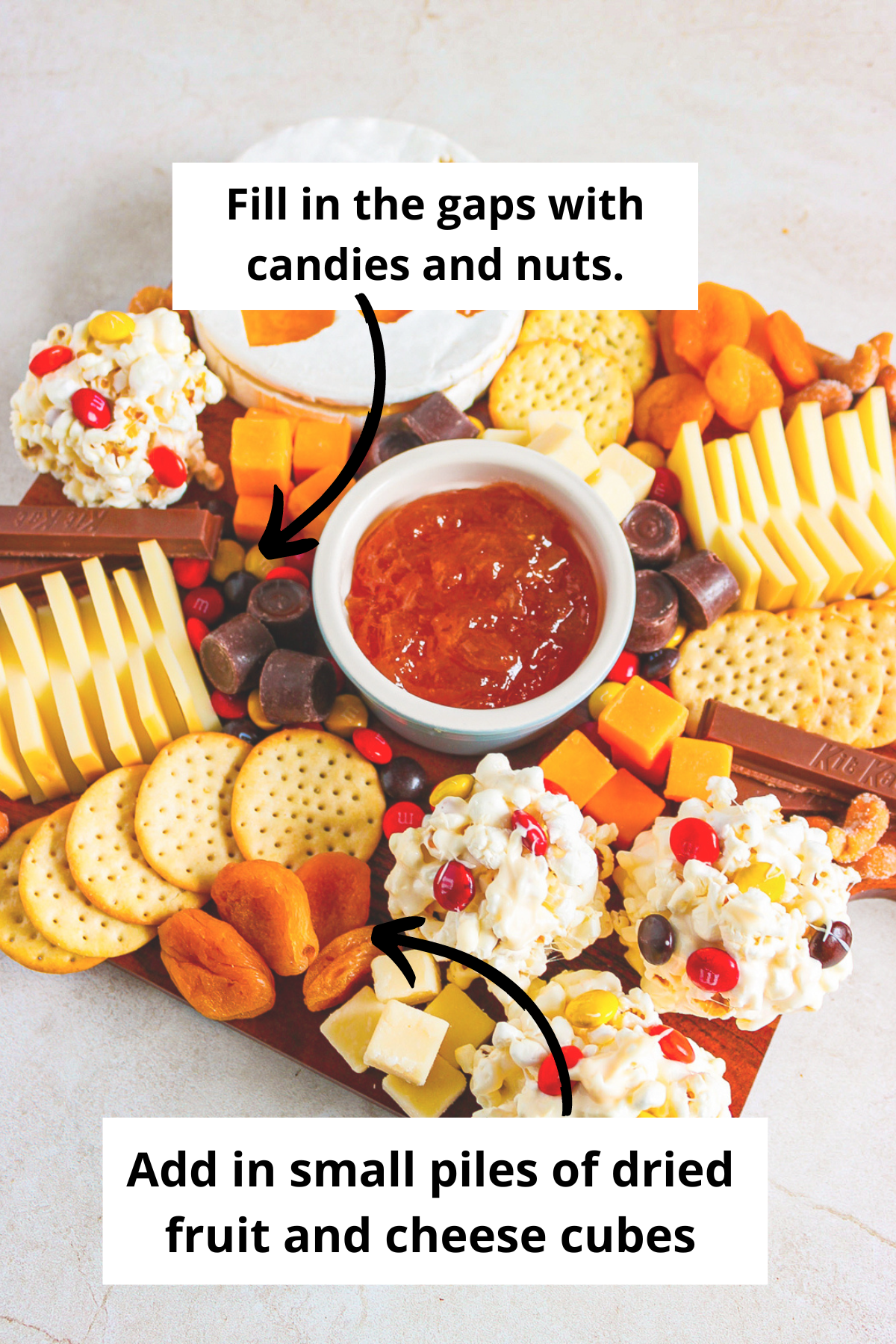 adding in the candy, nuts, fruit and cheese cubes to the festive halloween snack board