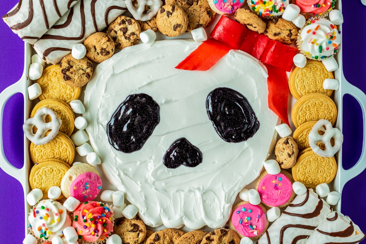 spooky skull dessert board served with halloween cookies, cupscakes and small candies.