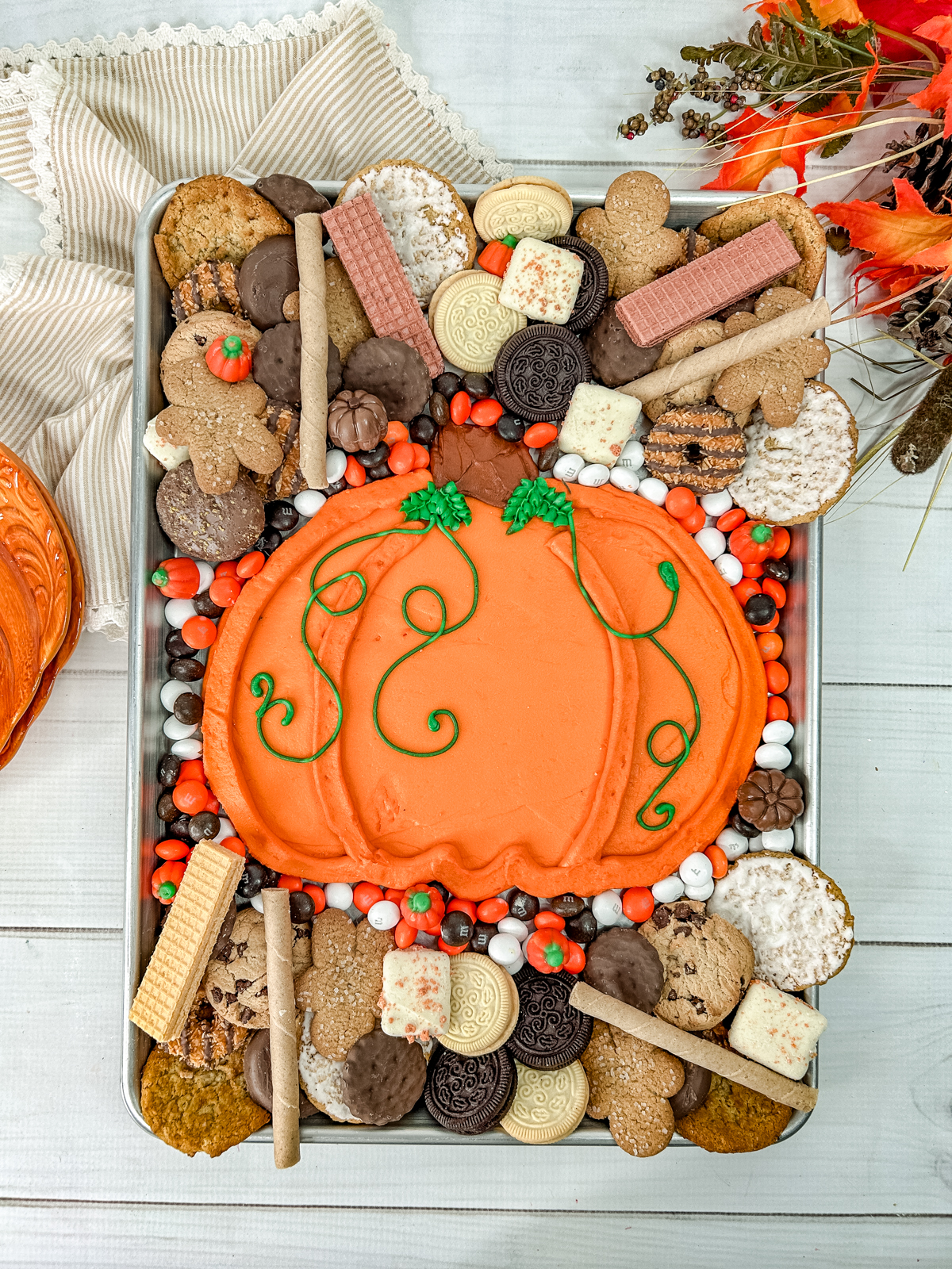 cookies and small candies decorate this pumpkin buttercream board