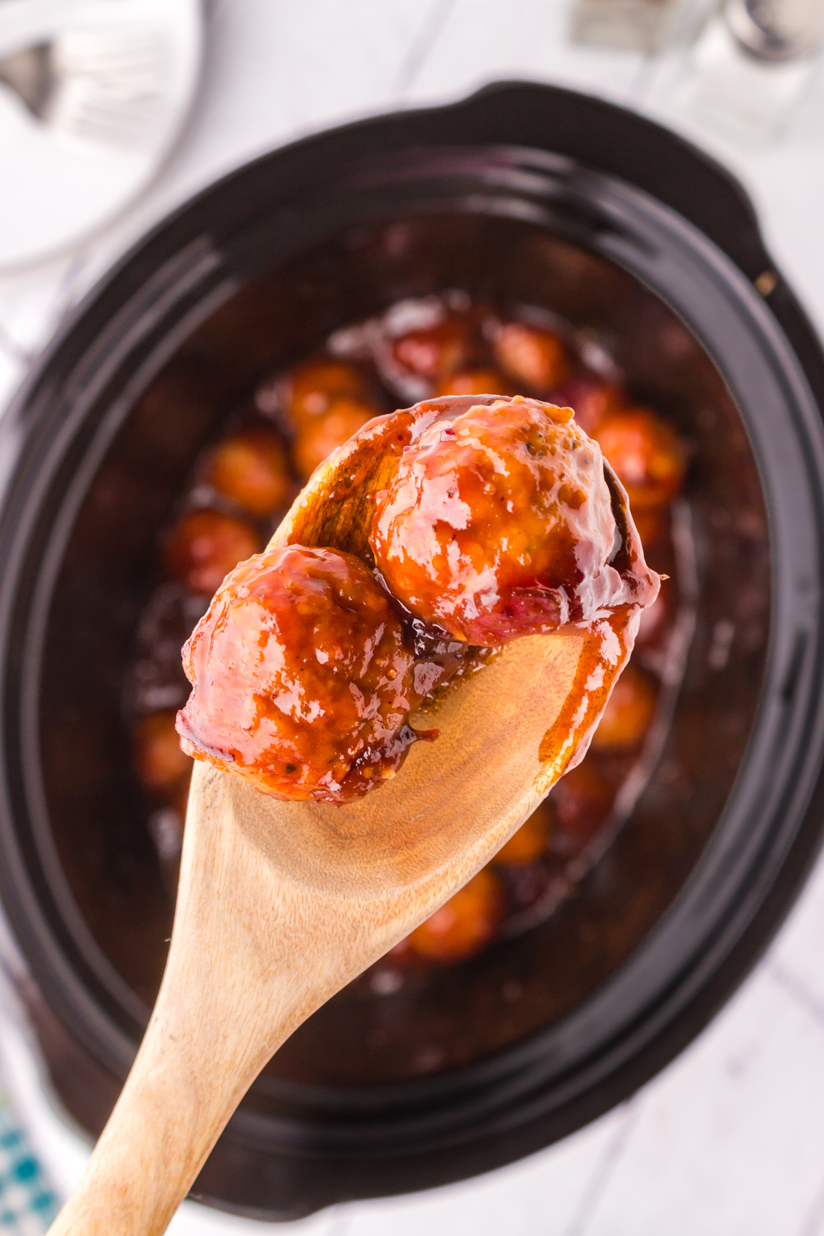 cranberry BBQ crock pot meatballs on a serving spoon