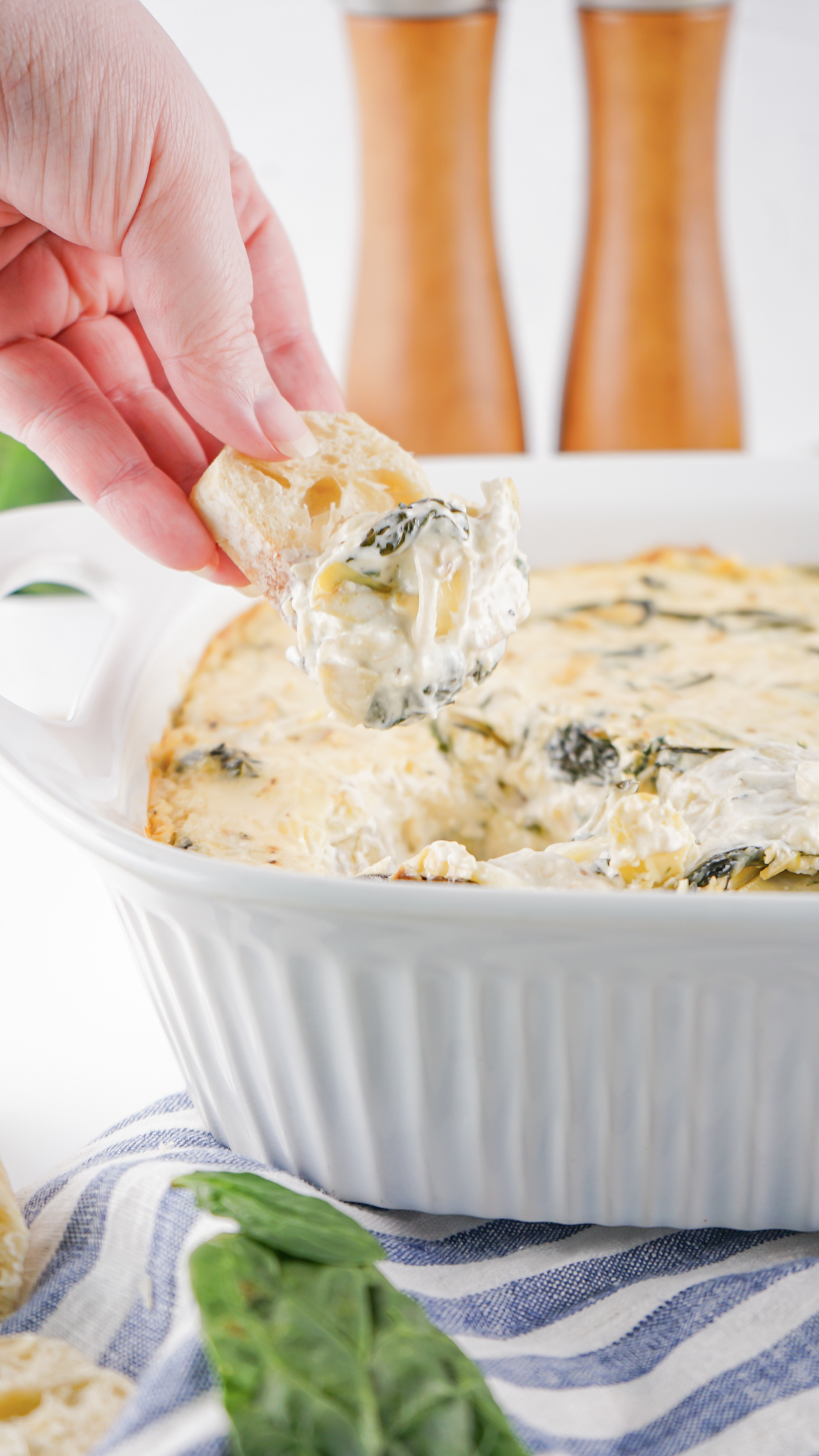 baked cheesy spinach artichoke dip scooped on a slice of bread