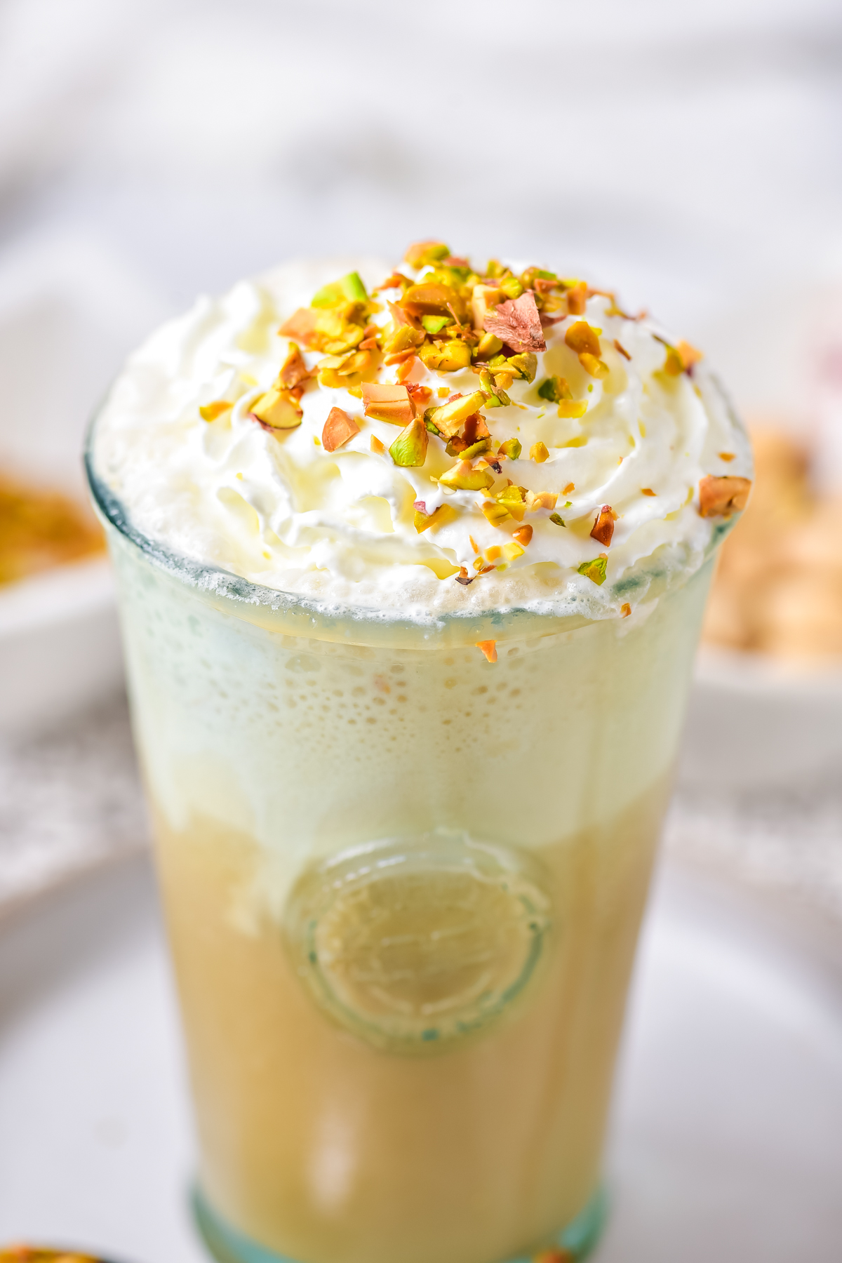 close up of a glass of iced pistachio latte topped with chopped pistachios