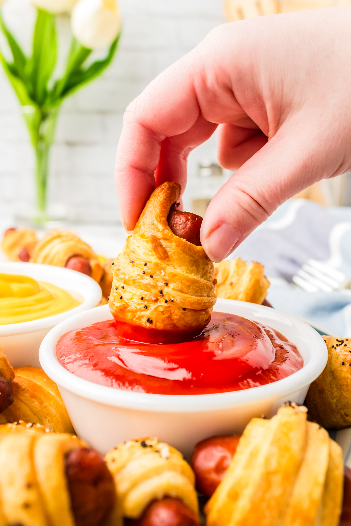 dipping an air fryer pigs in a blanket into dipping sauce