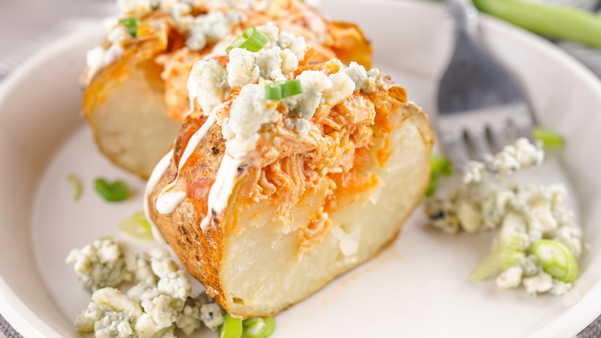 delicious buffalo chicken baked potatoes sliced in half on a plate