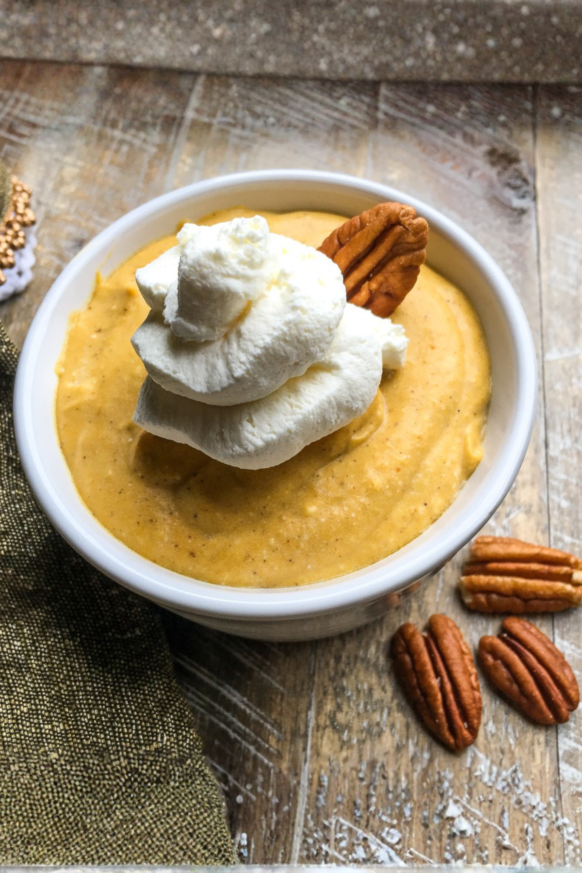 homemade pumpkin mousse topped with whipped cream and pecans in a bowl on the table