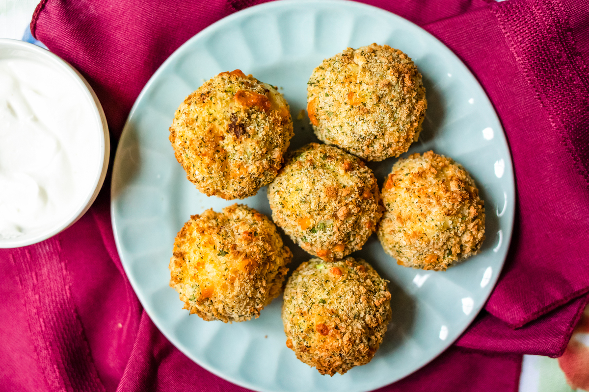 mashed potato balls on a plate with dipping sauce on the side